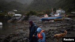 Un hombre y su hijo en el pueblo de Sotomó, Chile, se dirigen a una escuela primaria el 6 de agosto de 2021. La comunidad ha recibido el servicio de internet gratis mediante un programa del multimillonario estadounidense Elon Musk.