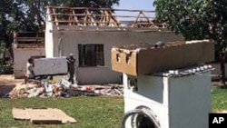 FILE: Farm workers clean up at Les de Jager's "Two Trees" farm in the Lions Den area, 150 kilometers north of Harare, Zimbabwe after looters ransacked the house, stripping the home and causing damage to farm equipment. The looters abandoned the washing machine on the lawn.