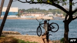 A cyclist walks along the seafront in Santo Domingo on July 29, 2020. Dominican Republic's Emergency Operation Center increased the alert level from yellow to red ahead Tropical Storm Isaias.