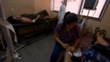 Valeria Medina, de 36 años, infectada con dengue, descansa en una camilla médica mientras espera el tratamiento de la enfermera Daniela Caldera, en el hospital Dr. Oscar H. Costas, en Joquín V. González, Salta, Argentina, el 16 de marzo de 2024.