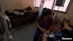 Valeria Medina, de 36 años, infectada con dengue, descansa en una camilla médica mientras espera el tratamiento de la enfermera Daniela Caldera, en el hospital Dr. Oscar H. Costas, en Joquín V. González, Salta, Argentina, el 16 de marzo de 2024.