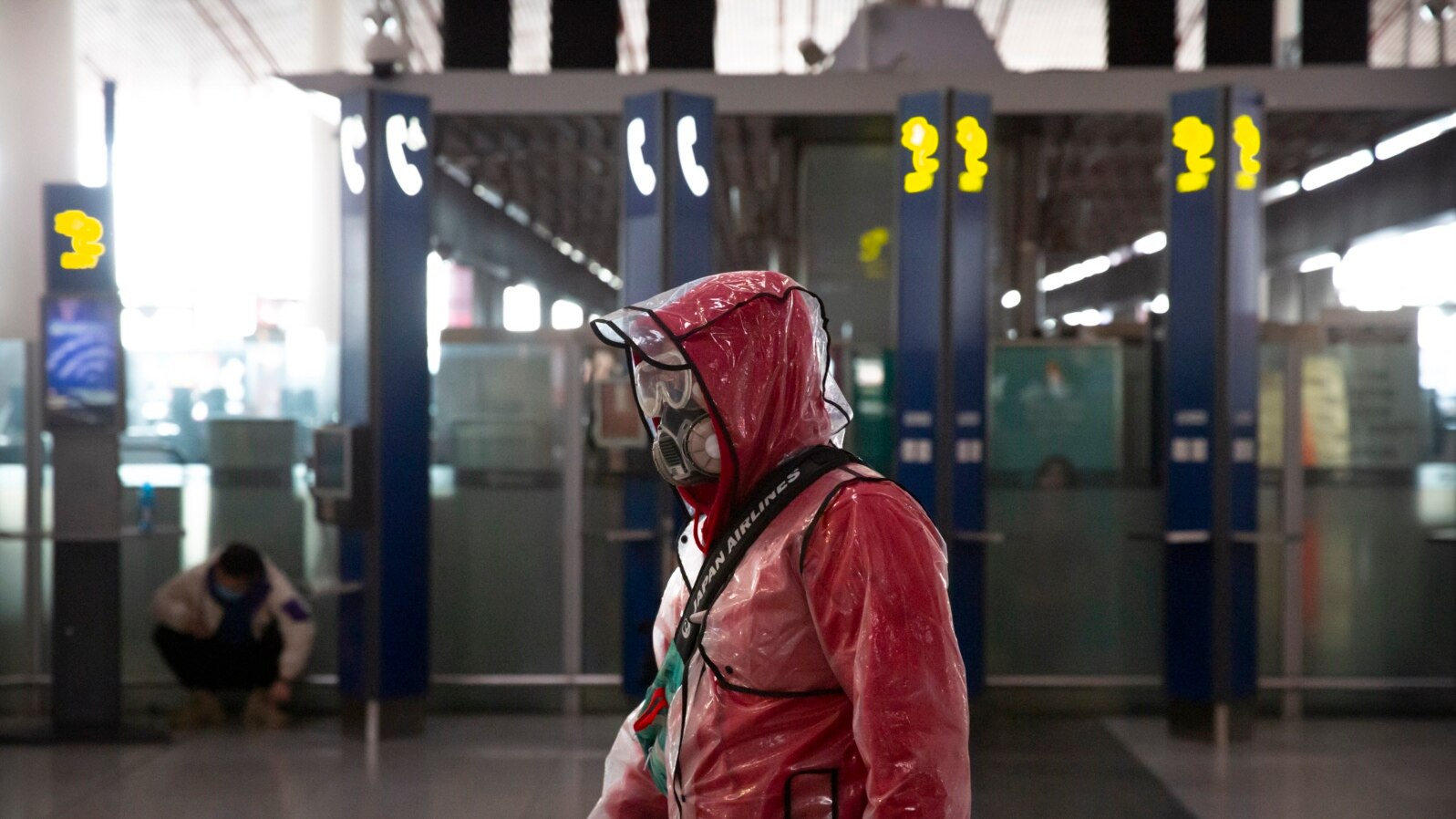 A traveler wears a respirator, goggles, and a raincoat as he walks through Beijing Capital International Airport, in Beijing, China, March 28, 2020.