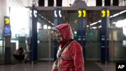 A traveler wears a respirator, goggles, and a raincoat as he walks through Beijing Capital International Airport, in Beijing, China, March 28, 2020.