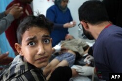 FILE —A young boy reacts as a child receives medical attention at the Kuwaiti hospital for wounds sustained in an Israeli bombardment that hit a camp sheltering displaced Palestinians near the Emirati hospital, in Rafah in the southern Gaza Strip on March 2, 2024.