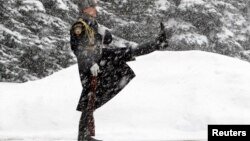 An honor guard marches during the changing of the guards ceremony at the Tomb of the Unknown Soldier by the Kremlin wall during snowfall in central Moscow, Mar. 25, 2013. 