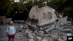 Seorang wisatawan berjalan melintasi struktur bangunan masjid yang hancur seteleh dilanda gempa bumi di Pulau Kos, Yunani, 22 Juli 2017 (foto: AP Photo/Petros Giannakouris) 