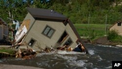 FILE - A house sits in Rock Creek after floodwaters washed away a road and a bridge in Red Lodge, Montana, June 15, 2022. The state attorney general is appealing a ruling that said state agencies aren't doing enough to protect young plaintiffs from harm caused by global warming.