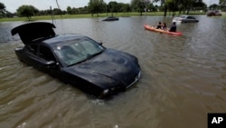 Domingo Molina paddles with his granddaughters down a flooded street in Houston, May 26, 2015. 