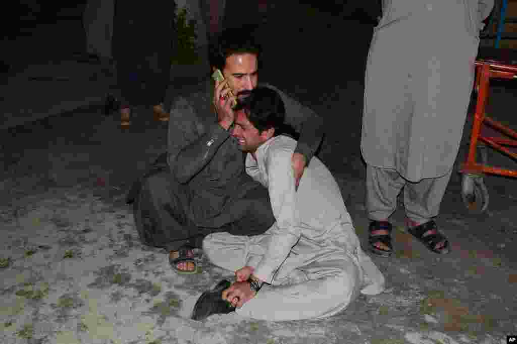 A Pakistani man comforts another mourning the death of a family member in a bomb blast, at a hospital in Quetta, April 21, 2021. A powerful bomb went off in the parking area of a five-star Serena Hotel in the southwestern city, killing five people.