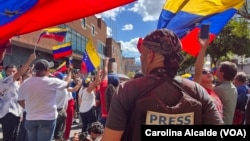 ARCHIVO - Un miembro de la prensa observa a manifestantes en una protesta política en Venezuela. 