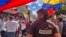 ARCHIVO - Un miembro de la prensa observa a manifestantes en una protesta política en Venezuela. 