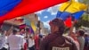 ARCHIVO - Un miembro de la prensa observa a manifestantes en una protesta política en Venezuela. 