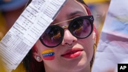 ARCHIVO - Una mujer muestra copias de las actas de votación de la elección presidencial de julio en Venezuela, que la oposición dice haber ganado, durante una manifestación en Bogotá, Colombia, el 17 de agosto de 2024.