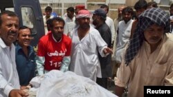 Petugas medis tengah memindahkan korban penembakan pria tak dikenal dari mobil ambulans ke ruang jenazah rumah sakit di Quetta, Pakistan (6/8). Sedikitnya 13 orang dikabarkan tewas dibunuh saat bus yang mereka tumpangi dalam perjalanan menuju propinsi Punjab.