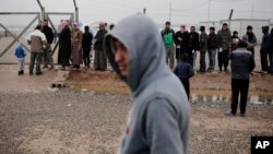 Displaced people wait for aid at a camp east of Mosul, Iraq, Feb. 15, 2017. The United Nations says they are temporarily pausing aid operations to neighborhoods in eastern Mosul retaken from the Islamic State group for security reasons.