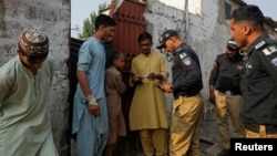 FILE - Pakistani police officers, along with workers from the National Database and Registration Authority, check the identity cards of Afghan citizens during a search and verification drive for undocumented Afghan nationals, near Karachi, Pakistan, Nov. 21, 2023.