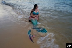 FILE - Lauren Metzler, founder of Sydney Mermaids, prepares for a swim at Manly Cove Beach in Sydney, Australia, Thursday, May 26, 2022. (AP Photo/Mark Baker)