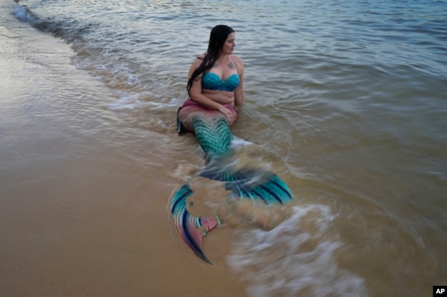 FILE - Lauren Metzler, founder of Sydney Mermaids, prepares for a swim at Manly Cove Beach in Sydney, Australia, Thursday, May 26, 2022. (AP Photo/Mark Baker)