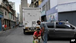 Men siphon gasoline from a car in the San Juan neighborhood of Caracas, Venezuela, Jan. 19, 2021.