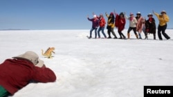 Piter Condori takes photos of tourists behind a toy dinosaur for a fee, at the Uyuni Salt Flat in Bolivia March 27, 2022. (REUTERS/Claudia Morales)