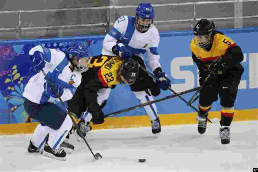 Jenni Hiirikoski of Finland, (L-R) Tanja Eisenschmid of Germany, Michelle Karvinen of Finland and Manuela Anwander of Germany battles for control of the puck during the 2014 Winter Olympics women's ice hockey game at Shayba Arena, Sunday, Feb. 16, 2014, i