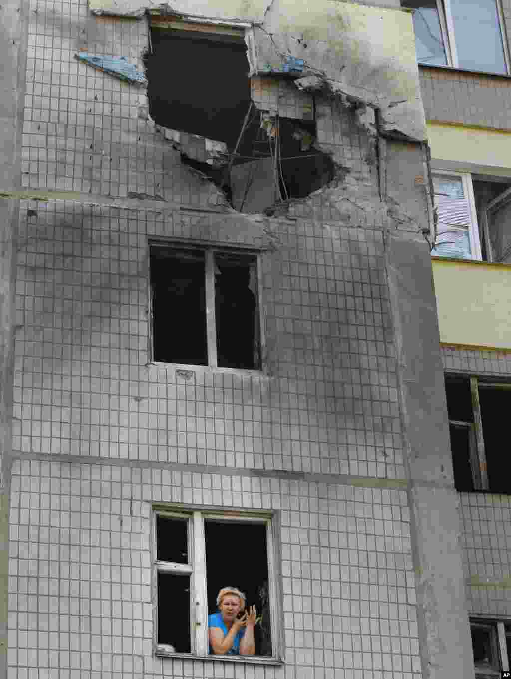 Local resident Marina Barsuk looks out of the broken window of her flat after shelling in Donetsk, eastern Ukraine, Aug. 8, 2014.