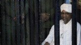 Sudan's former president Omar Hassan al-Bashir sits guarded inside a cage at the courthouse where he is facing corruption charges, in Khartoum, Aug. 19, 2019.