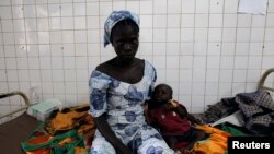 FILE - A woman sits beside her sick child in the pediatric ward at the general hospital in Man, western Ivory Coast, July 4, 2013. 