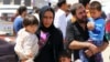 A family fleeing the violence in the Iraqi city of Mosul waits at a checkpoint in outskirts of Arbil, in Iraq's Kurdistan region, June 10, 2014. 