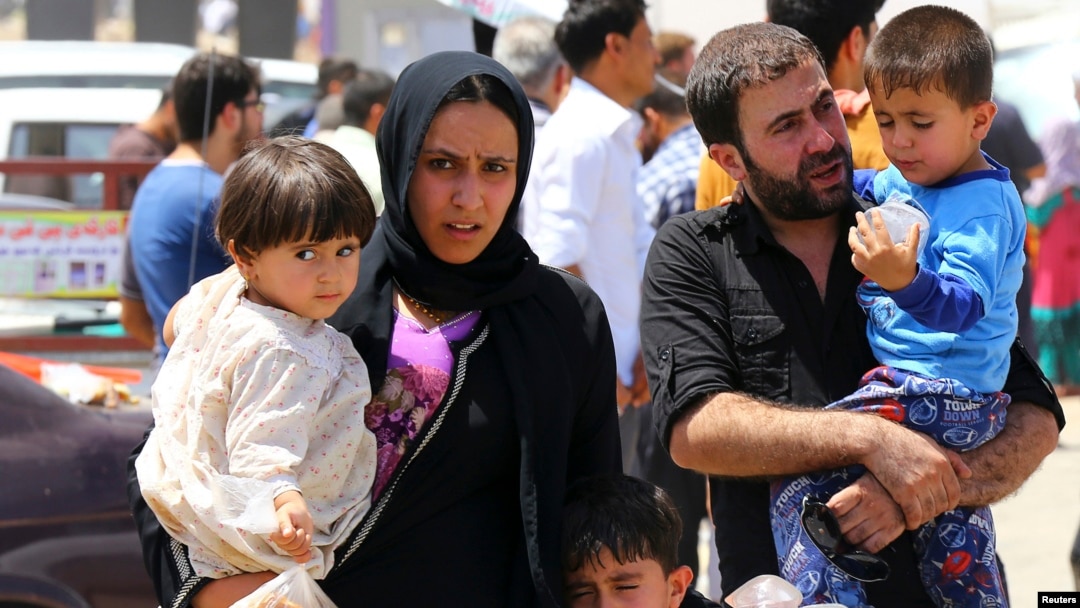 A family fleeing the violence in the Iraqi city of Mosul waits at a checkpoint in outskirts of Arbil, in Iraq's Kurdistan region, June 10, 2014. 