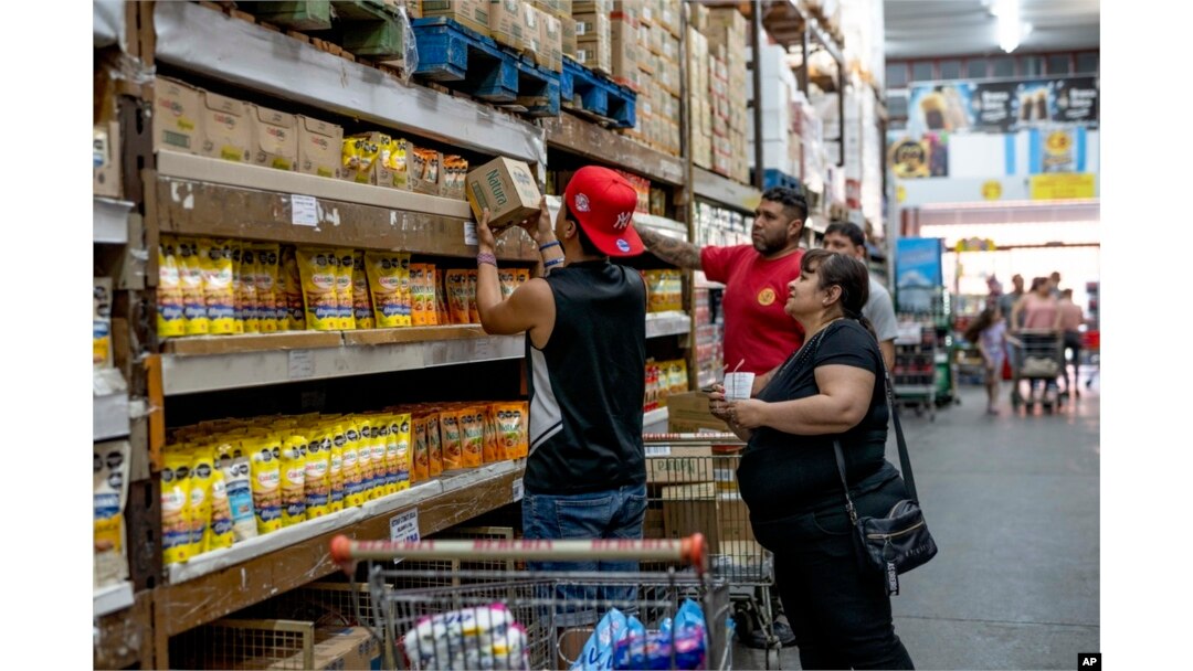 FILE - People buy groceries at a supermarket that accepts 'chachos' currency in La Rioja, Argentina, Sept. 23, 2024.
