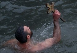 Greek Orthodox faithful Nikolaos Solis, a pilgrim from Agrinio, Greece, retrieves a wooden crucifix as he swims in the Golden Horn during the Epiphany ceremony in Istanbul, Jan. 6, 2020.