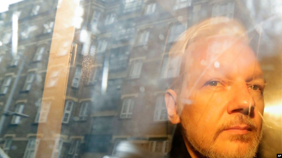 ARCHIVO - En esta fotografía del miércoles 1 de mayo de 2019 se reflejan unos edificios en la ventana mientras el fundador de WikiLeaks, Julian Assange, se aleja de la corte en la que compareció por cargos de espionaje en Londres.