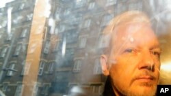 ARCHIVO - En esta fotografía del miércoles 1 de mayo de 2019 se reflejan unos edificios en la ventana mientras el fundador de WikiLeaks, Julian Assange, se aleja de la corte en la que compareció por cargos de espionaje en Londres.
