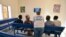 FILE - A UNHCR representative (C) speaks with refugees as they watch television in a waiting room of a UNHCR office in Niamey, Niger, Nov. 17, 2017, after being evacuated from Libya.