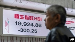 A pedestrian passes by an electronic screen displaying the Hang Seng Index on the first trading day of the Year of Snake in Hong Kong, Feb. 3, 2025. 