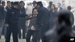 Police officers take away a female petitioner from a court house, where jailed activist Wang Lihong attends her court appeal case on charges of creating a disturbance when she helped lead a protest on behalf of three bloggers, in Beijing, China, Thursday,