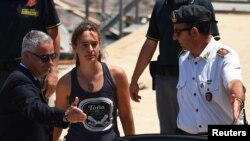 Carola Rackete, the 31-year-old Sea-Watch 3 captain, disembarks from a Finance police boat and is escorted to a car, in Porto Empedocle, Italy, July 1, 2019. 