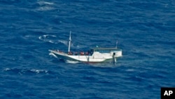 In this July 4, 2012 file photo released by the Indonesian National Search and Rescue Agency, a wooden boat which is believed to have up to 180 asylum seekers on board floats on the waters off Christmas Island, Australia.