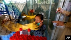 FILE - A girl reacts while having a nasal swab sample taken by a health worker at a COVID-19 testing facility in a hospital in Karachi, Pakistan, March 18, 2021. 