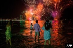 People celebrate as they watch the traditional New Year's fireworks at Copacabana Beach in Rio de Janeiro, Dec. 31, 2019.