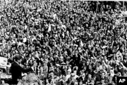 FILE - U.S. President John F. Kennedy, left, waves to a crowd of more than 300,000 gathered to hear him declare "Ich bin ein Berliner," "I am a Berliner," in front of Schoeneberg City Hall, West Berlin, June 26, 1963.