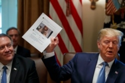 FILE - Secretary of State Mike Pompeo, left, looks at a paper held by President Donald Trump about Rep. Ilhan Omar, D-Minn., as Trump speaks during a Cabinet meeting in the Cabinet Room of the White House, July 16, 2019.