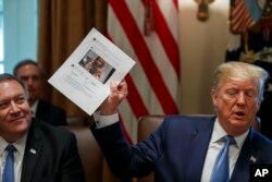 FILE - Secretary of State Mike Pompeo, left, looks at a paper held by President Donald Trump about Rep. Ilhan Omar, D-Minn., as Trump speaks during a Cabinet meeting in the Cabinet Room of the White House, July 16, 2019.