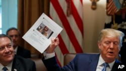 Secretary of State Mike Pompeo, left, looks at a paper held by President Donald Trump about Rep. Ilhan Omar, D-Minn., as Trump speaks during a Cabinet meeting in the Cabinet Room of the White House, July 16, 2019, in Washington.