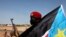 A South Sudanese soldier sits behind a South Sudan flag in Bentiu, Unity state, Jan. 12, 2014. South Sudan intercepted 11 U.N. trucks carrying weapons, headed to Bentiu. 