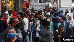 Grupos de personas, la mayoría protegidos con máscaras, llenan una popular calle de tiendas en Sao Paulo, Brasil, el 15 de julio de 2020.