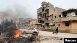 A man pulls a wheelbarrow past destroyed buildings after clashes between forces loyal to Libya's eastern government and Islamist fighters, in Benghazi, Feb. 28, 2016. Islamic State militants have expanded their control amid Libya's strife. 