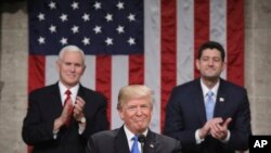 Presiden Donald Trump berhenti sejenak saat menyampaikan pidato kenegaraan pertamanya di kantor DPR AS, gedung Capitol, Washington DC, di hadapan para anggota Kongres Amerika, Selasa, 30 Januari 2018, sementara Wakil Presiden Mike Pence (belakang, kiri) dan Ketua DPR Paul Ryan (belakang, kanan) yang mendampinginya, bertepuk tangan.