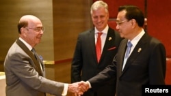 U.S. Secretary of Commerce Wilbur Ross shakes hands with China's Premier Li Keqiang, as U.S. National Security advisor Robert O'Brien watches, as they attend a bilateral meeting on the sidelines of the 35th Association of Southeast Asian Nations …
